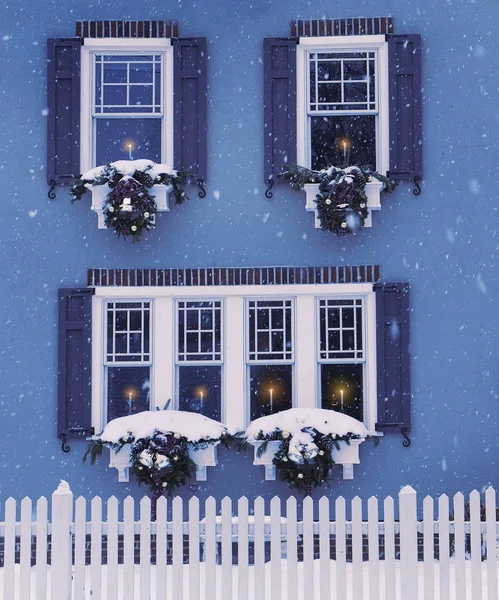 A small cozy house, windows decorated with Christmas wreaths and candles in the windows. USA. Maine. traditional celebration.