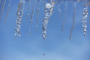 Eriyen buz sarkıtları mavi gökyüzü. Bahar tezcan başlangıcı.