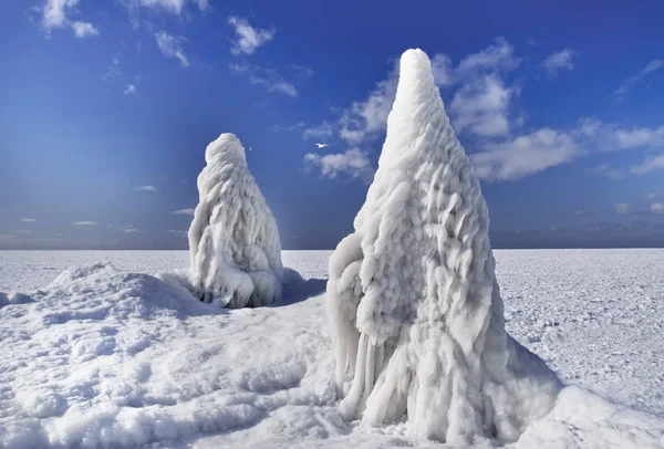 Gigan ice blocks in the form of ice cream on the icy pier and view of the frozen sea. Winter sea fairy landscape.