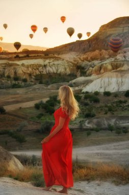 Kız kırmızı elbise fırtınası ve dansları balonlar ve kayalar bakan sabahın erken saatlerinde. Cappadocia.