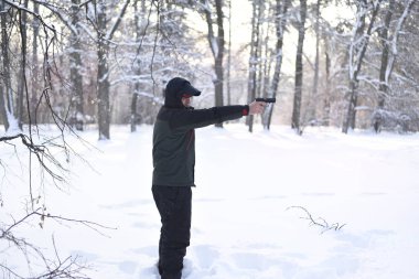 Onun elinde silahlı bir adam kış ormanda hedefliyor.