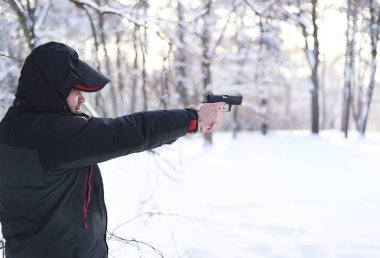 Onun elinde silahlı bir adam kış ormanda hedefliyor.