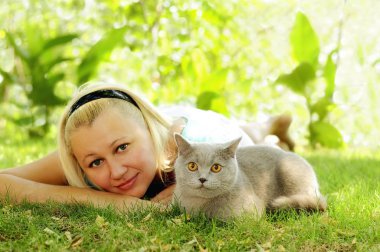 Kız ile bir peluş Gri kedi güneşli Bahçe Yeşil çimenlerin üzerinde dinlenme.