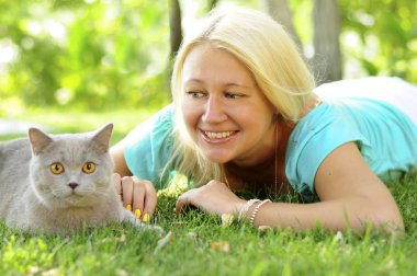 Kız ile bir peluş Gri kedi güneşli Bahçe Yeşil çimenlerin üzerinde dinlenme.