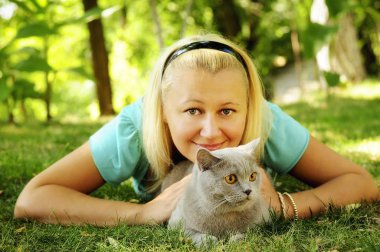 Kız ile bir peluş Gri kedi güneşli Bahçe Yeşil çimenlerin üzerinde dinlenme.