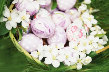 Elma ve yeşil çimen çiçekler arasında özgün Paskalya yumurtaları.