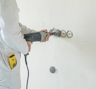 Bir adam delikli bir duvar örer. Bir adam inşaat aletleriyle çalışıyor..