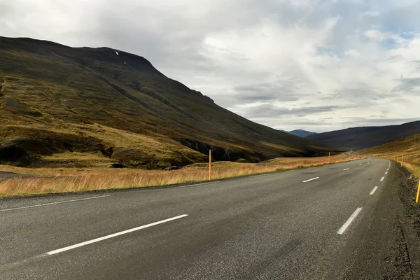 a deserted asphalt road running away into the hills. Iceland. The spirit of travel and adventure.