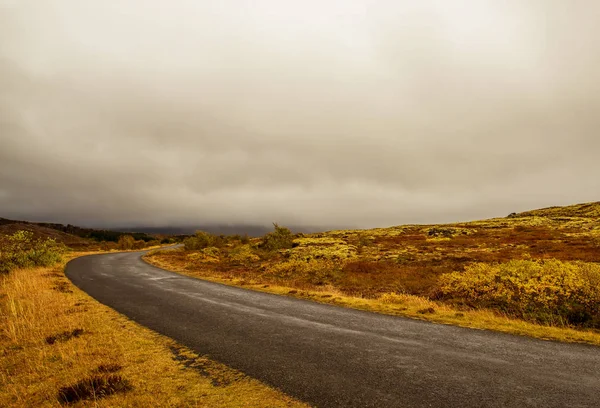 a deserted asphalt road running away into the hills. Iceland. The spirit of travel and adventure.