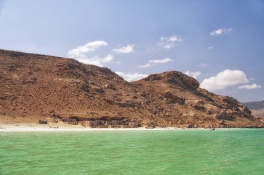 Vahşi kayalar arasında sahilde basit bir balıkçı köyü. Arap Denizi kıyılarında sıradan insanların balıkçıların hayatlarını düzenlemek. Sahilde taş evler. Yemen. Ada Socotra.