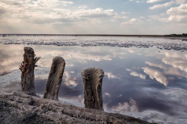 Eski ahşap mesajlar bir tuz gölün kıyısında madencilik tuz sonra sol. Su yüzeyinde bulutların yansıması.