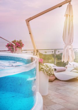 Havuz kenarında rahat bir dinlenme yeri. Deniz manzaralı vazolar içinde küçük şeffaf havuz ve çiçekler