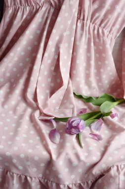 Polka noktaları ile nazik pembe elbise ve duş yaprakları ile düşen pembe lale.