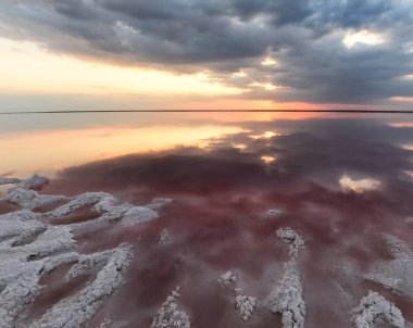 Gün batımında pembe su ve tuz ile benzersiz tuz gölü. Tuz gölünün pembe suyunda bulutların muhteşem yansıması.