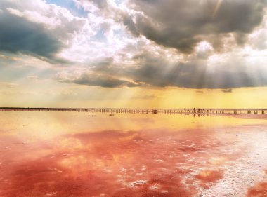 Gün batımında pembe su ve tuz ile benzersiz tuz gölü. Tuz gölünün pembe suyunda bulutların muhteşem yansıması.