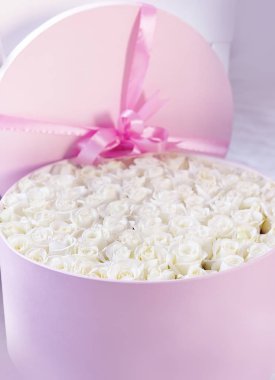 Büyük şapka şeklinde pembe bir kutu içinde beyaz küçük gül bir sürü.