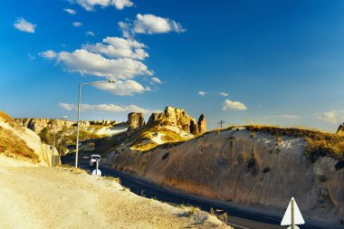 Kapadokya'da kayaların arasında tur otobüsü ve yol. Kapadokya Sıcak güneşli manzara. Mağara kaya şehirler.