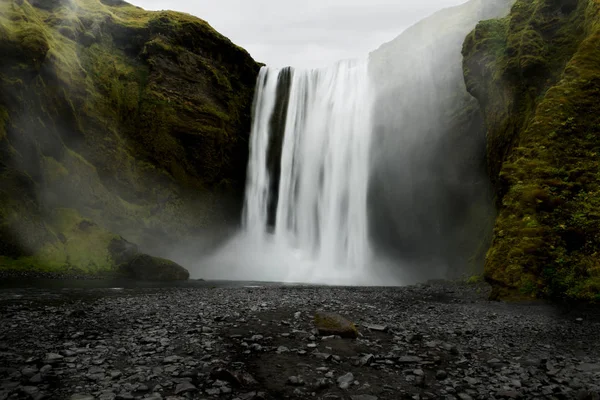 A powerful waterfall among the rocks covered with green moss. Iceland. Dark fabulous atmosphere, vintage.