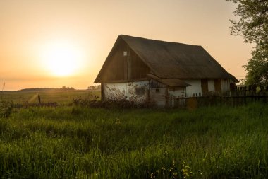 Gün batımında bir tarlada eski bir kırsal ahır. Kırsal bir evin eski bir fotoğrafı. Ukrayna.