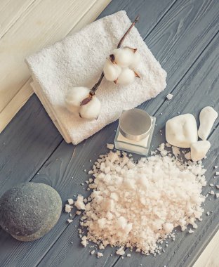 Gri ahşap zemin üzerinde kaplıca taşları ve deniz tuzu olan güzel bir kompozisyon. Spa arka planı. Spa element koleksiyonunun üst görünümü 