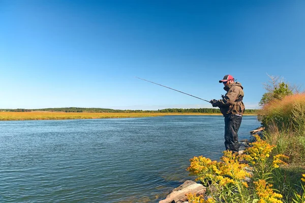 貯水池の岸の漁師は晴れた日に釣りをしている — ストック写真