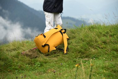 Sırt çantası ve yürüyüş direkleri dağların yüksek kesimlerinde. Ve arka planda bir turist figürü. Dağlarda ve doğada aktif eğlence ortamı..