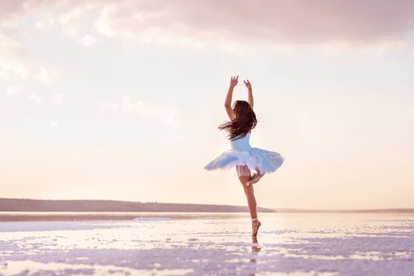 Girl ballerina in a ballet dress dances in the water of the lake