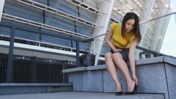 Азиатская бизнес-леди снимает каблуки усталых ног — стоковое видео