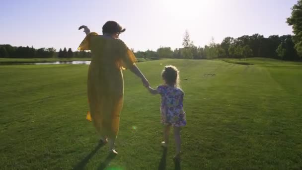 Filha e mãe correndo no prado de grama verde — Vídeo de Stock