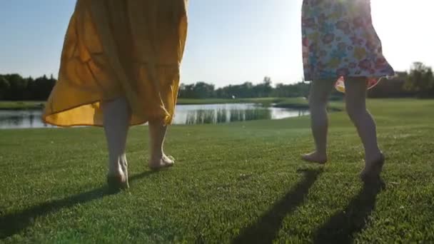 Gros plan sur les jambes de la mère et de l'enfant courant sur l'herbe — Video