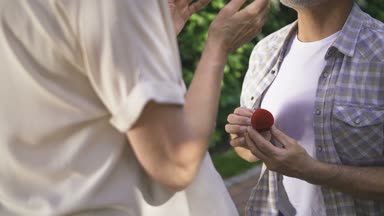 Diz üstünde duran ve onun kadınla evlenme teklifi yapma gri sakallı yakışıklı komuta sizde. Üst düzey çiftin samimi nişan. Yaşlı adam açık havada nişanlısı parmağında yüzük koyarak ve onu kucaklayan