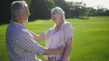 Çekici üst düzey çift yeşil çimenlerin üzerine gülüyor