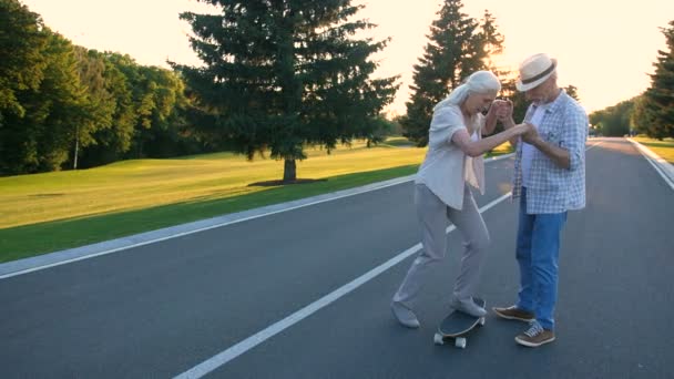 Ανώτερος γυναίκα Μαθαίνοντας να skateboard με το σύζυγό — Αρχείο Βίντεο