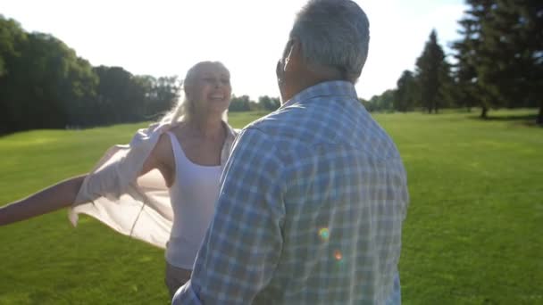 Gelukkige senior paar verliefd knuffelen op groen gazon — Stockvideo