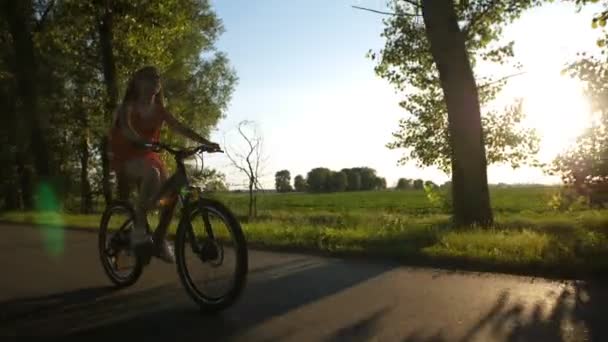 Εμπρόσθια όψη του κορίτσι έφηβος σε ένα ποδήλατο κατά το ηλιοβασίλεμα — Αρχείο Βίντεο