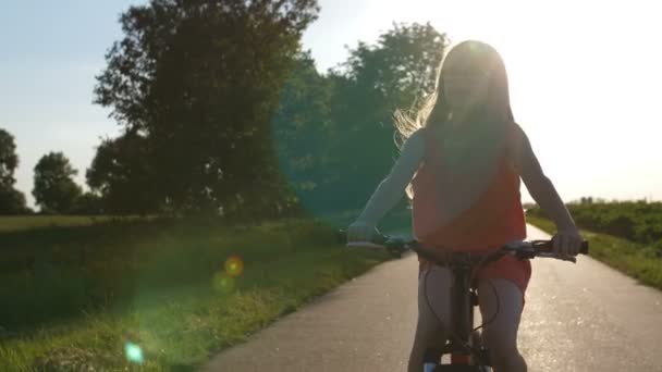 Tiener fietsen tijdens zonsondergang op platteland — Stockvideo