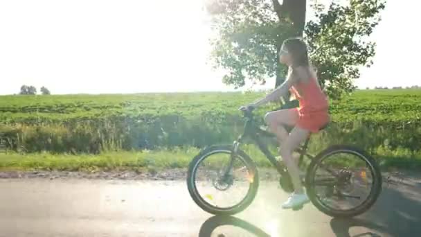 Teen flicka cykling genom fälten i sommar — Stockvideo