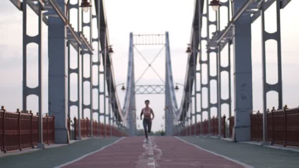 Fitness femenina trotando al amanecer en el puente — Vídeos de Stock