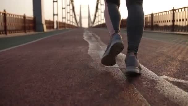 Κοντινό πλάνο γυναικεία πόδια τζόκινγκ στην Ανατολή του ηλίου στη γέφυρα — Αρχείο Βίντεο