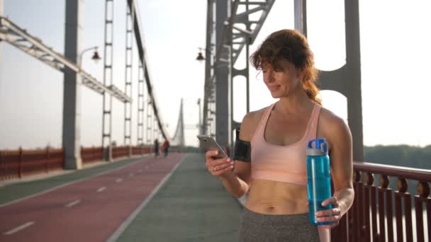 Üst düzey kadın spor app üstünde hareket eden telefon kullanarak — Stok video