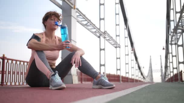 高级红发妇女锻炼后喝水 — 图库视频影像