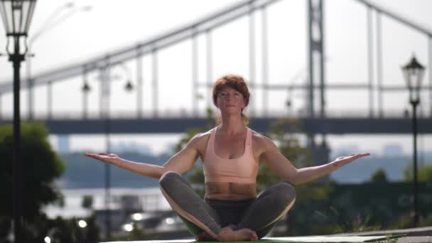 Mujer madura en pose de loto meditando en la ciudad — Vídeos de Stock