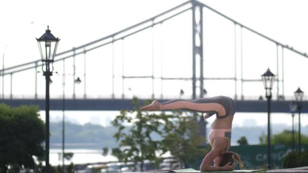 Rossa yogi femmina esecuzione headstand in città — Video Stock
