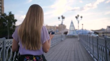 Sarışın kadının cellphone ile yürüyüş arkadan görünüm