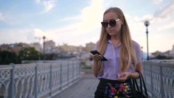 Mujer de negocios en gafas de sol caminando con teléfono — Vídeos de Stock