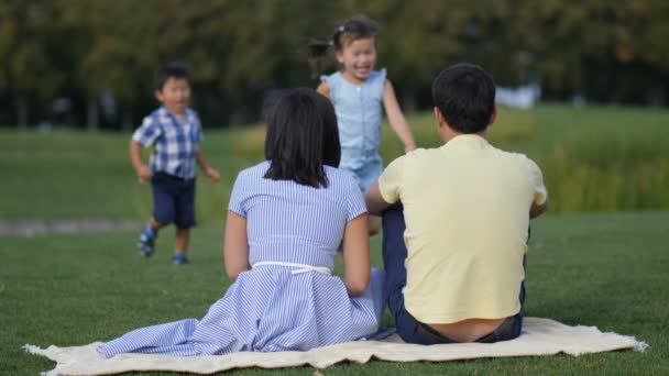 Милі азіатські діти ніжно обіймають батьків в парку — стокове відео