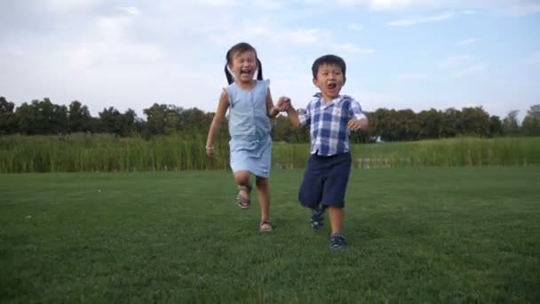 Radostné asijské děti běží spolu v parku — Stock video