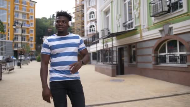 Vrolijke zwarte man genieten van muziek op straat stad — Stockvideo