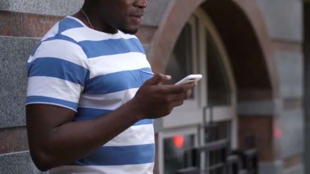 Хороший чорний чоловік слухає музику на вулиці — стокове відео