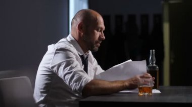 Duygusal ofis masasında mali belgeleri gözden geçirme orta yaşlı işadamı vurguladı. Perişan, onun kravat kaybetme ve umutsuzca kapalı seyir şirket borçları girişimci ile aşırı.